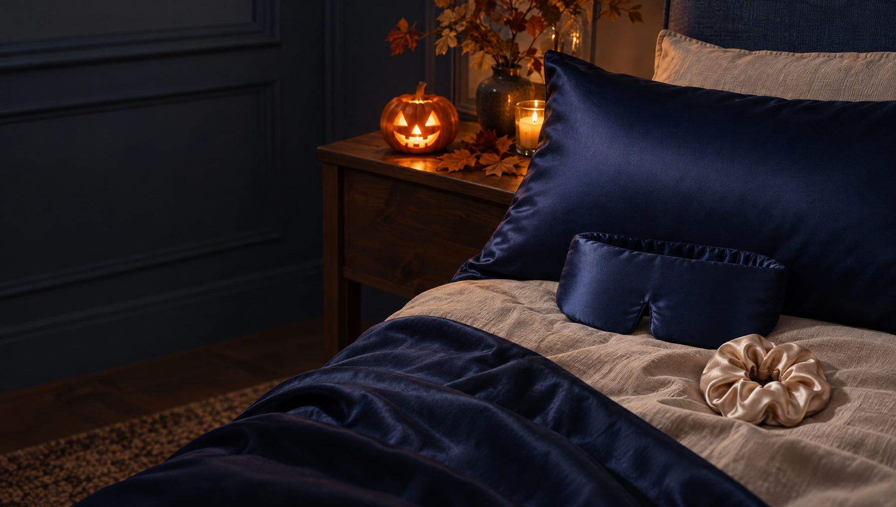 Le masque et la taie en soie Saphir Nuit sur un lit, un chouchou en soie, une citrouille à la bougie sur la table de nuit